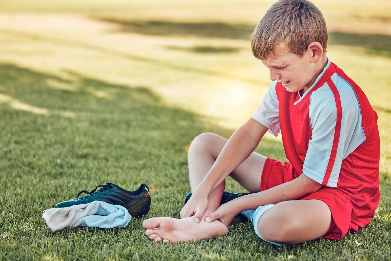 Young footballer holding an injured foot and ankle on the field